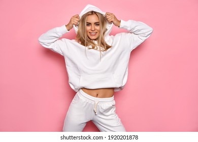 Sexy blonde woman wear of white set of tracksuit isolated on pink pastel background