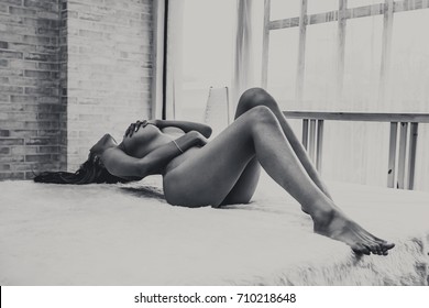 Sexy body nude Asian woman. Portrait of a sexy female legs in her bedroom on white brick wall background in rural room