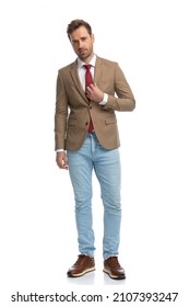 Sexy Businessman Arranging His Jacket And Posing With Cool Attitude Against White Background