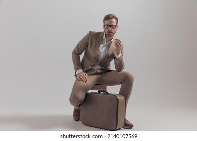 Sexy Businessman Posing On A Chair With His Luggage Between His Legs And A Cool Attitude 