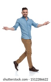 sexy casual man with blue shirt walking and greeting happy on white studio background