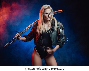 Sexy and charming woman with blond hairs in cyberpunk style poses in dark blue background holding glowing blade on her shoulder.