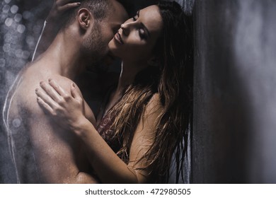 Sexy couple embracing and kissing under shower
