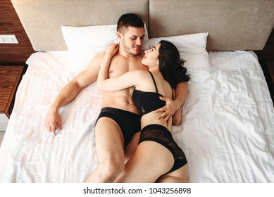 Sexy couple lying and kissing on big white bed