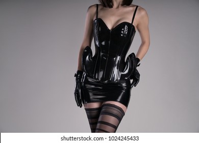 Sexy dominatrix woman in black corset, mini skirt and gloves, studio shot 