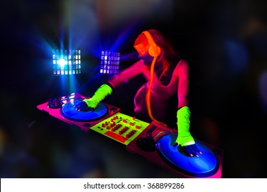 sexy female DJ mixes in a club  in UV fluorescent costume