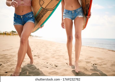 Sexy female surfers in hot short pants on a beach