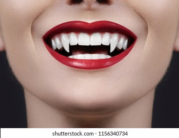 Sexy Female Vampire Lips. Monster Smile. Halloween Style with Red Blood Makeup Lip. Masquerade Look with Terrible Fangs on Black Background