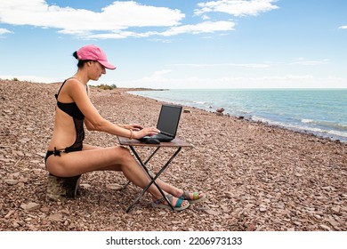 Sexy Freelance Girl In An Erotic Swimsuit Working At A Computer On The Ocean, Free Work Not Tied To A Place Of Residence