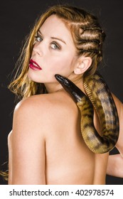 Sexy girl with black-headed python around her neck showing her back and looking at camera.