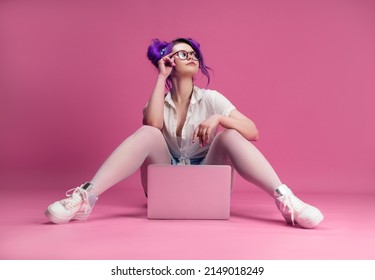 Sexy Girl With Glasses And Purple Hair With A Laptop On A Pink Background