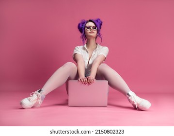 Sexy Girl With Glasses And Purple Hair With A Laptop On A Pink Background