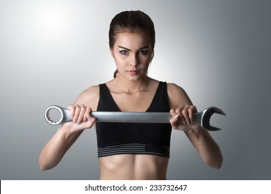 Sexy girl holding wrench spanner tool. Attractive woman working as repairman or mechanic. on gray background with clipping path