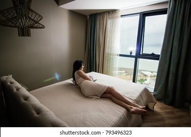 Sexy girl in a light dress lies on the bed with sea views