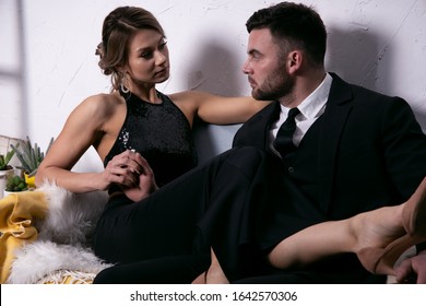 Sexy Girl Put Her Feet On Her Elegant Man's Lap Sitting On The Couch. Retro Portrait Of A Couple In Love