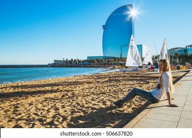 Sexy Girl Sitting At The Beach In Barcelona, Spain With A W Hotel On The Background. 