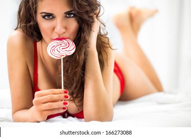 Sexy Lady Licking A Lollipop While Lying In Bed 