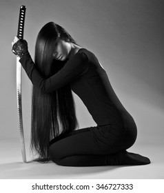 Sexy Long Haired Ninja Girl Or Assassin Woman Kneeling And Holding Katana Sword In Hand. La Femme Fatale