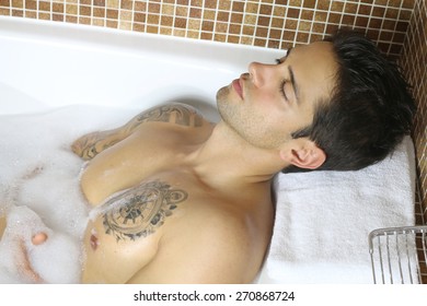 sexy man lying in a bath with foam