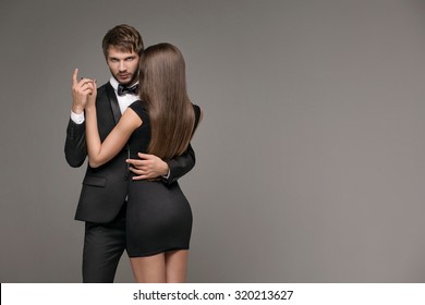 Sexy Man In A Suit Hugging A Mysterious Woman In A Little Black Dress