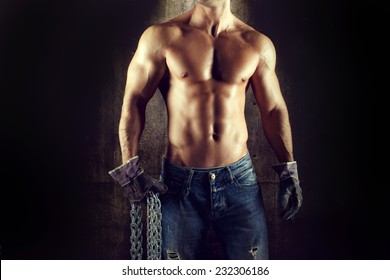 Sexy man worker body, in jeans and gloves with chain