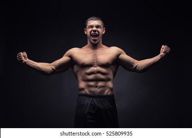 Sexy muscular male torso of athlete bodybuilder posing in power with veins on hands and bare chest on black background