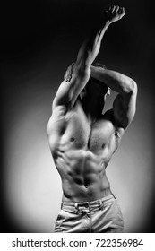 Sexy muscular male torso of athlete bodybuilder posing in power with veins on hands and bare chest on grey background