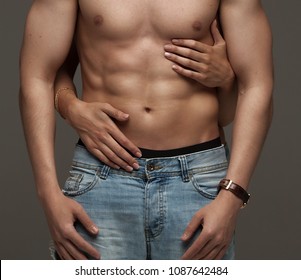 Sexy Muscular Naked Man And Female Hands Unbuckle His Jeans On A Dark Background