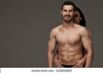 Sexy Muscular Naked Man And Female Hands Unbuckle His Jeans On A Dark Background