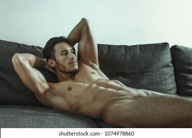 sexy and naked muscular young man posing on the sofa