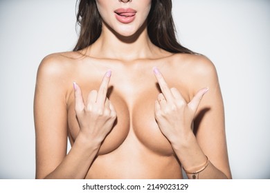 Sexy naked woman showing fuck off with the middle finger. Licking lips with tongue. Beautiful topless breast of slim sexy woman body. Isolated on white.