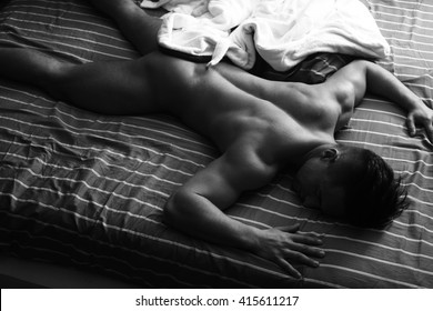 Sexy nude male model with ,muscular body in bed at home sleeping