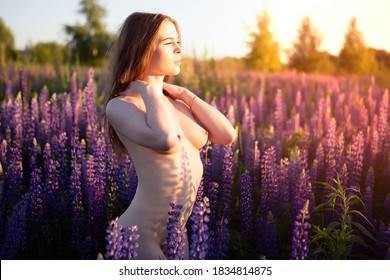 Sexy Nude young woman with beautiful elastic Breasts on a blooming field on a warm Sunny day