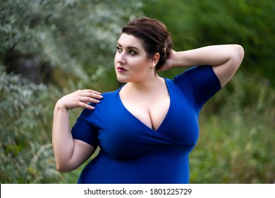 Sexy plus size fashion model in blue dress with a deep neckline outdoors, beautiful fat woman with big breasts in nature, body positive concept
