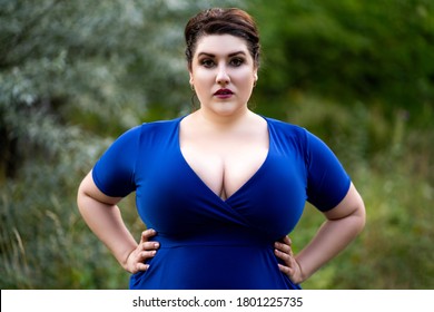 Sexy plus size fashion model in blue dress with a deep neckline outdoors, beautiful fat woman with big breasts in nature, body positive concept