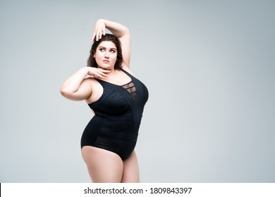 Sexy plus size fashion model in black one-piece swimsuit, fat woman in lingerie on gray background, body positive concept