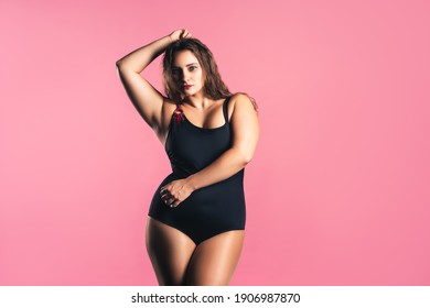 Sexy plus size fashion model in black one-piece swimsuit, fat woman in lingerie on pink background, body positive concept