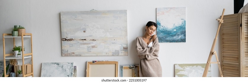 Sexy short haired artist in bra and sweater standing in workshop, banner - Shutterstock ID 2251005197