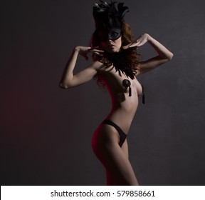 Sexy slim woman, burlesque dancer, unrecognizable stripper in mask and feathers