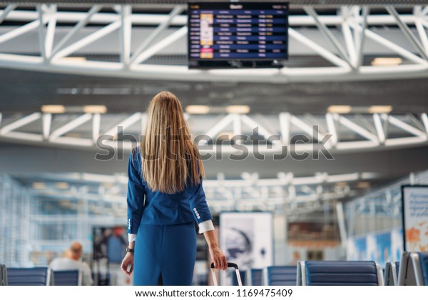 Sexy stewardess looks at scoreboard inairport