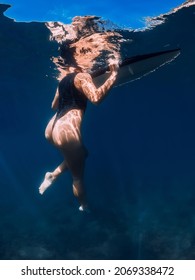 Sexy surfer girl swimming with board in blue sea. Underwater photo with woman and surfboard
