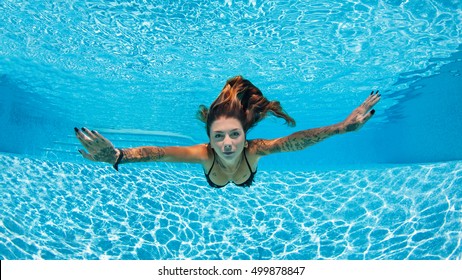 Sexy tattooed woman portrait wearing bikini underwater in swimming pool. Vacation, fun, lifestyle concept.