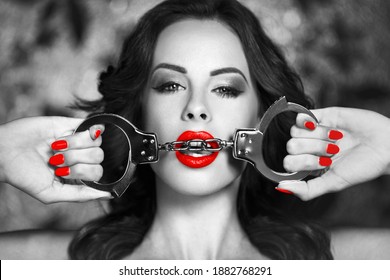 Sexy woman bite handcuffs, black and white selective coloring with red, bdsm