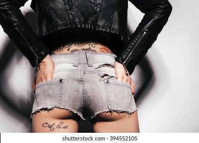 Sexy woman body with tattoo in jeans shorts. The model is back. Great ass. White background not isolated