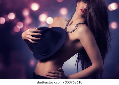 Sexy woman covers his naked body black hat dancing on the stage.