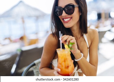 Sexy woman drinking cocktail in summer and enjoying her vacation