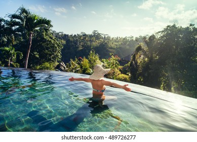 sexy woman enjoying the sun at infinity summer swimming pool at luxurious resort