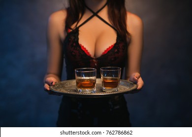 Sexy woman holding a tray of alcohol drinks. Bad habits. Immoral lifestyle. Elite night clubs for rich people concept