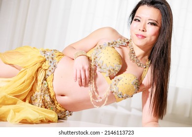 Sexy woman lying in yellow belly dance costume