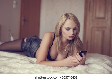 Sexy woman on bed write message by phone